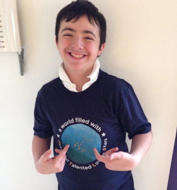 Smiling Boy pointing the PTLS foundation logo on his t-shirt